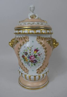 un vase blanc et doré orné d'une fleur rose et jaune