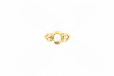 gros plan d'une bague en or contenant une perle
