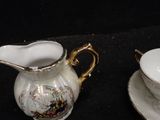 two cups and saucers sitting on a black table