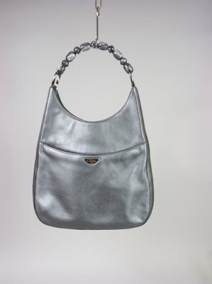 un sac à main argenté suspendu à une chaîne sur un mur blanc