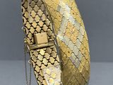 a close up of a gold bracelet on a clear stand