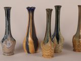 five different colored vases sitting in a row on a table