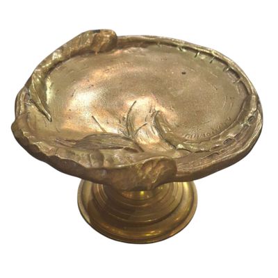 une assiette en or ornée d'un oiseau, posée sur un socle
