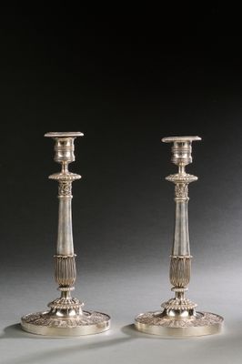 trois bougeoirs en argent posés sur une table, sur fond noir