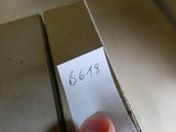 une main tenant un bout de papier sur lequel est inscrit un nom