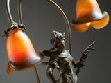 an art deco lamp with a lady holding a guitar and a bell shade