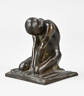 une statue en bronze représentant un homme agenouillé sur un livre
