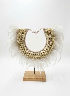 un gros plan d'un collier orné de plumes, posé sur un support en bois