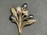 an image of a brooch with pearls and leaves