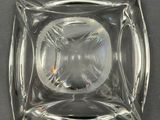 a glass ashtray on a table with a black background