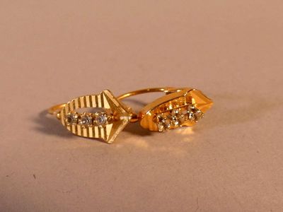 paire de boucles d'oreilles plaquées or, ornées de diamants, sur fond beige