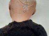 a close up of a doll with a black sweater on
