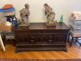 two statues sitting on top of a chest in a room
