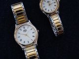 two watches sitting on a black surface next to each other