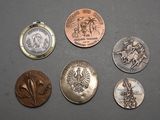 Plusieurs pièces de monnaie différentes sont posées sur une table, à côté d'une montre de poche.