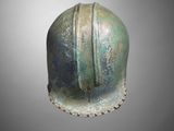 a close up of a bronze helmet on a gray background
