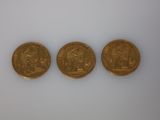 trois types différents de pièces d'or sur une surface blanche
