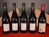 six bottles of wine are lined up on a red cloth