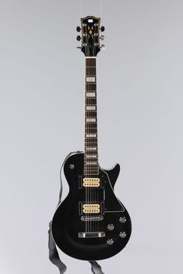 a black electric guitar hanging from a white wall