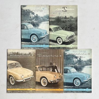 quatre anciennes brochures automobiles sont posées sur une surface blanche