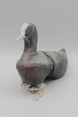 un vieux canard en bois posé sur une corde