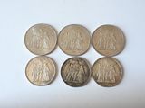 six different coins are arranged in a row on a white surface