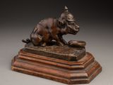 statue en bronze représentant un chien sur un socle, tenant un livre