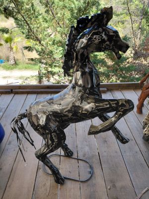 sculpture of a horse made out of scrap metal on a porch