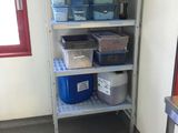 a metal shelf with plastic containers on it in a room
