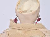 a close up of a doll wearing a dress and earrings