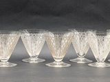 six clear wine glasses lined up in a row on a table