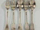 cinq cuillères en argent et une fourchette sont alignées sur une surface blanche