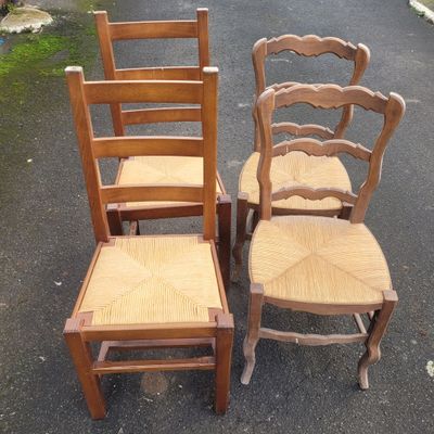 three wooden chairs sitting next to each other in a parking lot