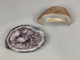 deux morceaux d'améthorate posés sur une surface blanche, à côté d'un morceau de roche