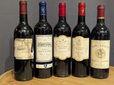 six bottles of red wine are lined up on a wooden tray