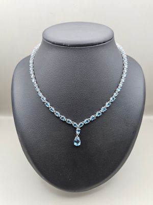 un collier orné d'une topaze bleue et d'une chaîne en argent, présenté sur un mannequin