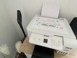une imprimante posée sur un bureau, à côté d'une plante