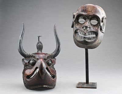 paire de masques africains ornés de cornes et d'un crâne, posés sur un socle