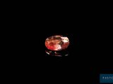 a pink diamond on a black surface with a black background