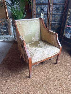 an old chair in a living room with a plant in the corner