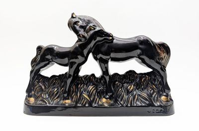 a black statue of a horse and a foal in the grass