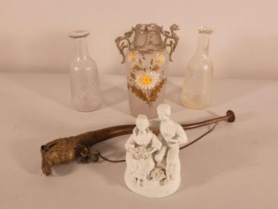 une petite statue représentant un homme tenant une canne, à côté d'un vase en verre
