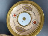 a gold plate with a design on it next to a vase