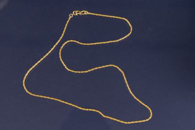 un collier en or avec une chaîne en or sur fond bleu
