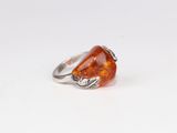 une bague en argent ornée d'une pierre orange et de feuilles