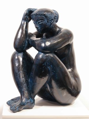 statue of a man sitting on a pedestal with his hand on his head