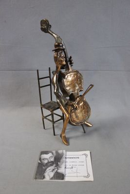 une statue représentant un homme assis sur une chaise avec une guitare