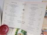 a book open to a menu and a red bowl on a table