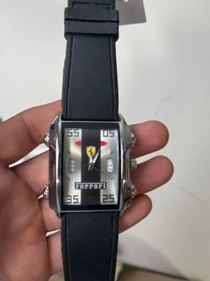 Quelqu'un tient dans sa main une montre arborant le logo Ferrari.