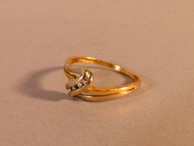 une bague en or ornée d'un nœud, posée sur une table